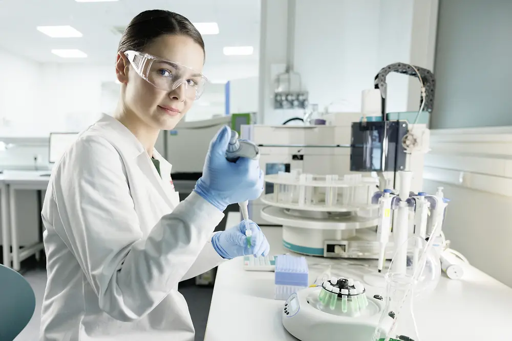 Egy női kutató kísérletezik egy laboratóriumban, laborköpenyt és védőszemüveget visel